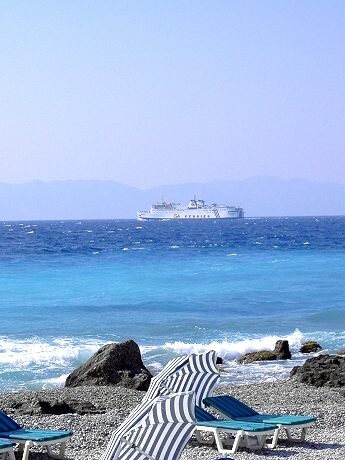 Rhodos-Stadt: Kieselstrand, im Hintergrund eine Fhre und die trkische Halbinsel Loryma